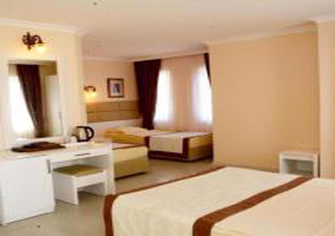 Miramor Hotel & Spa 안탈리아 외부 사진 The photo shows a hotel room with two beds and a cozy, inviting atmosphere. One bed is larger, possibly a queen or king size, and is draped with a light-colored bedspread that has a brown accent. The room has light-colored walls and natural light str